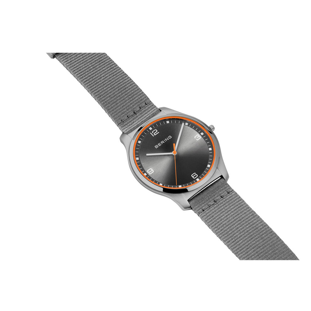 BERING watch with round dark dial, rose-gold bezel, and gray fabric strap, angled view