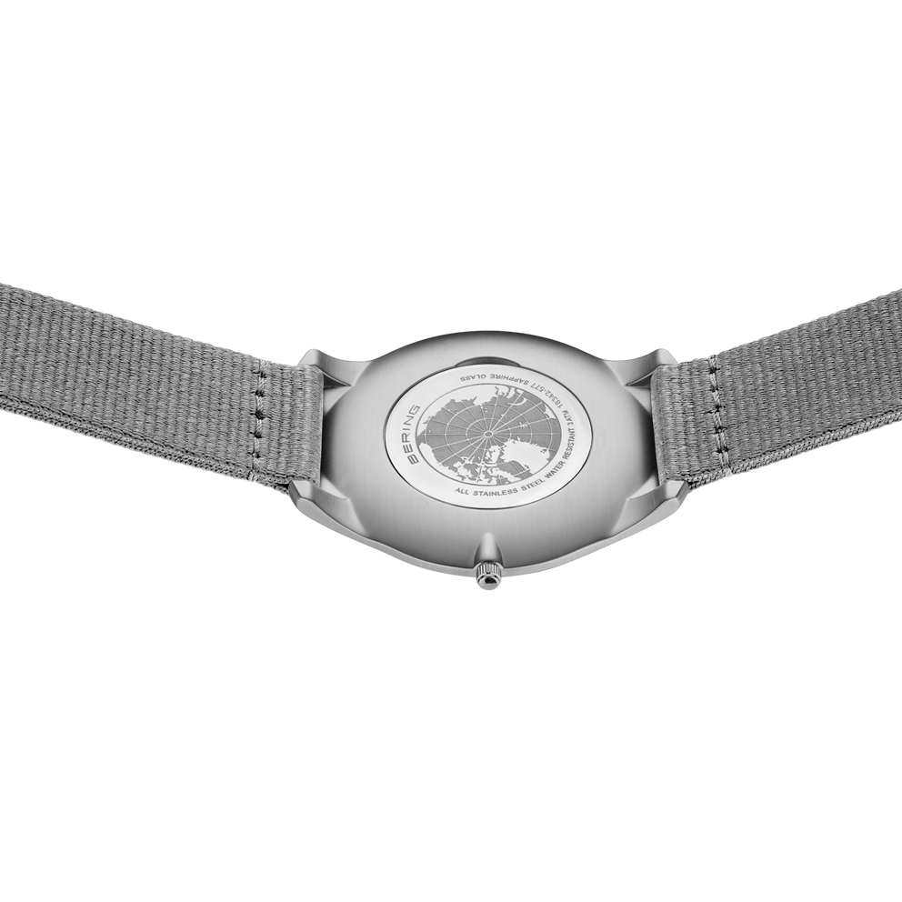 Watch caseback with transparent back showing internal mechanism, grey mesh band
