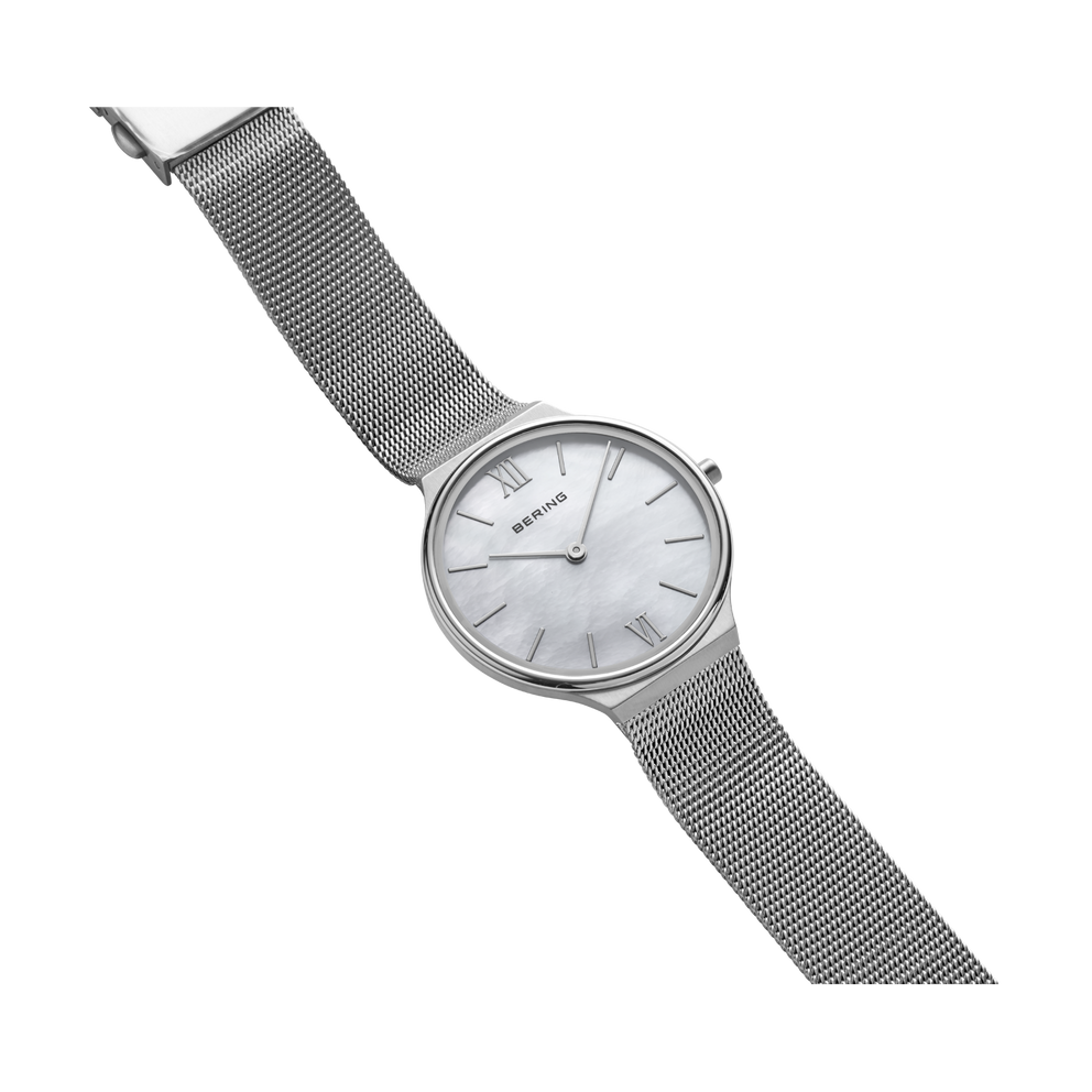 Reloj con esfera redonda y correa gris de malla, vista en ángulo
