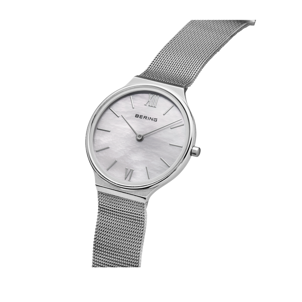 Reloj BERING modelo 18434-000 con esfera clara y correa de malla metálica, vista angular del reloj y correa.