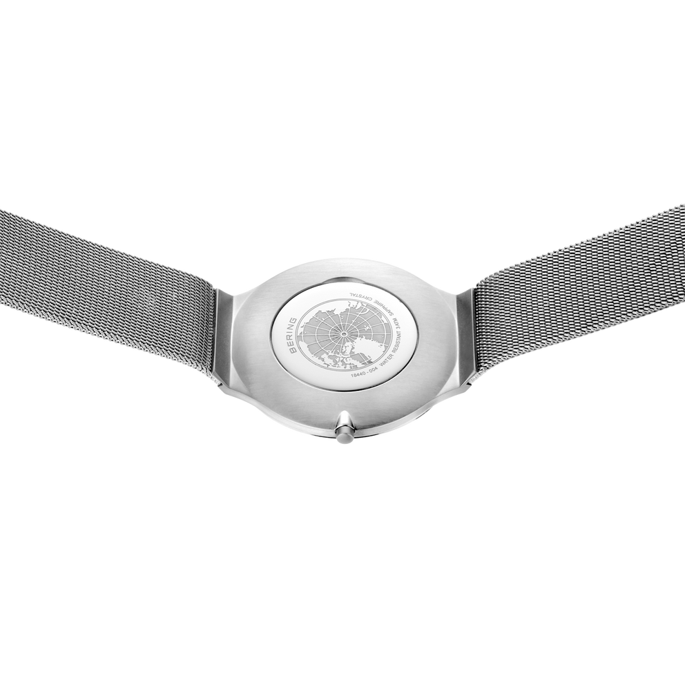 Stahlarmbanduhr mit gemustertem Zifferblatt und grauem Mesh-Armband, von oben fotografiert.