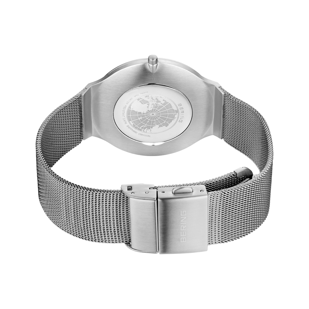Silberne Armbanduhr mit rundem Gehäuse und Weltkartenzifferblatt, Mesh-Metallarmband, von oben fotografiert.