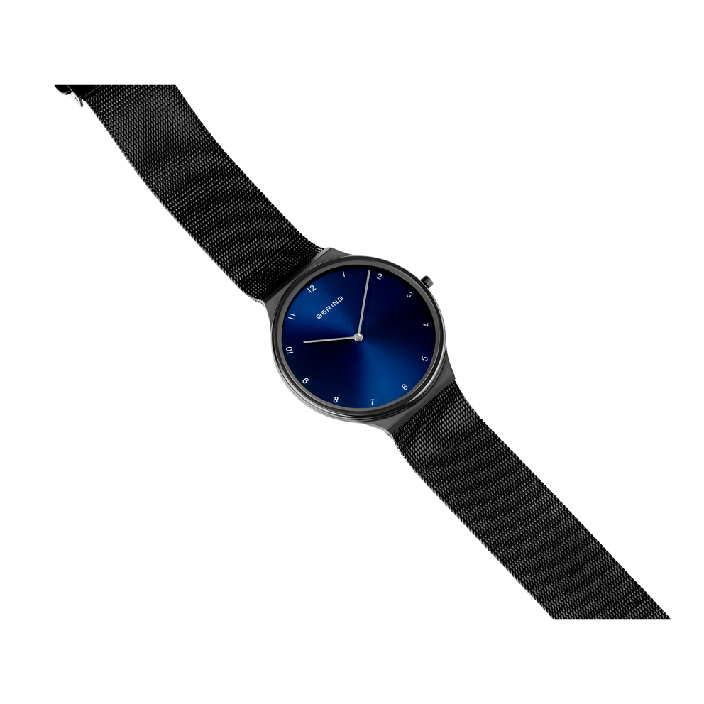 Reloj BERING con esfera azul oscuro, caja plateada y correa de tela negra, mostrado en ángulo.