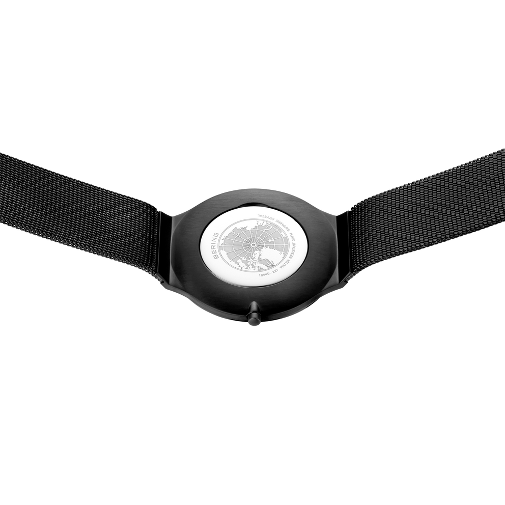 Reloj negro con caja redonda, esfera plateada y correa textil negra, vista frontal