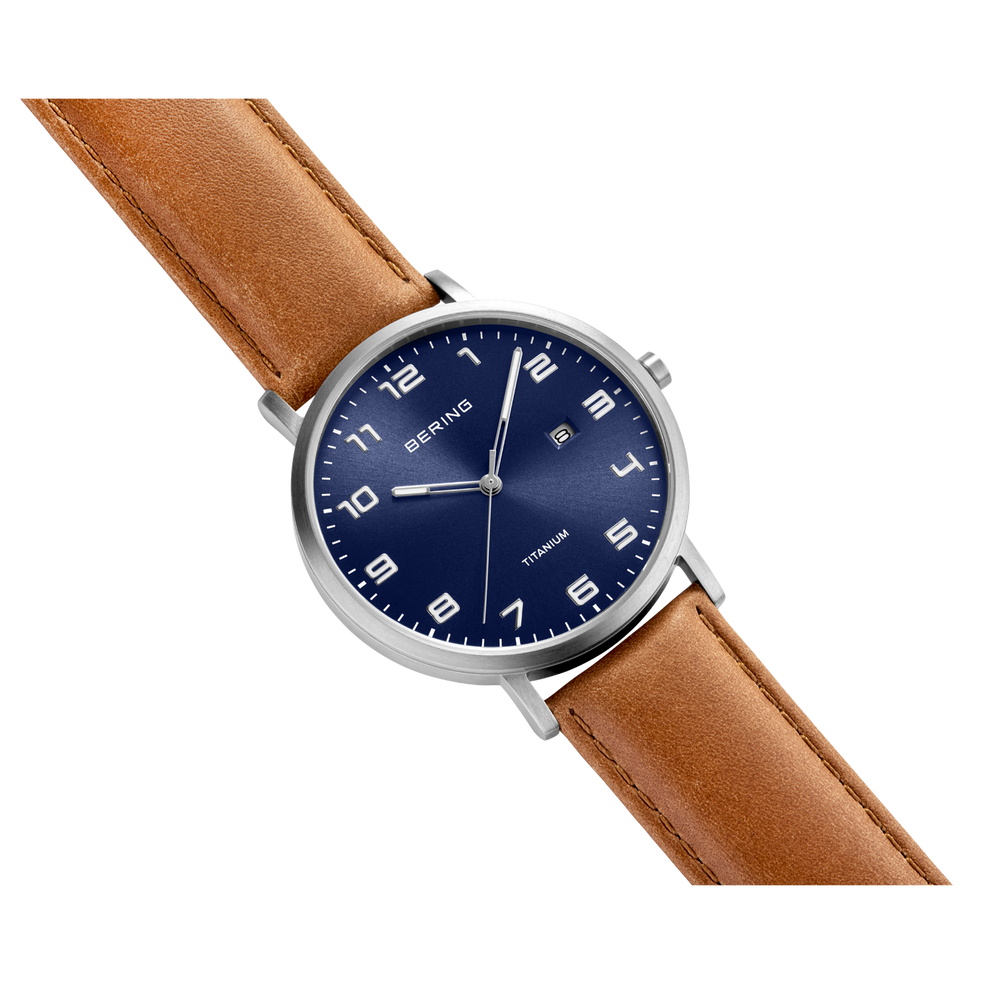 BERING round watch with silver case, navy dial, and brown leather strap shown at an angle