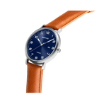 BERING wristwatch with silver case, navy dial with numerals, and tan leather strap, shown at angle.
