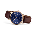 BERING wristwatch with rose gold case, blue dial with Arabic numerals, and brown leather strap, shown at an angle.