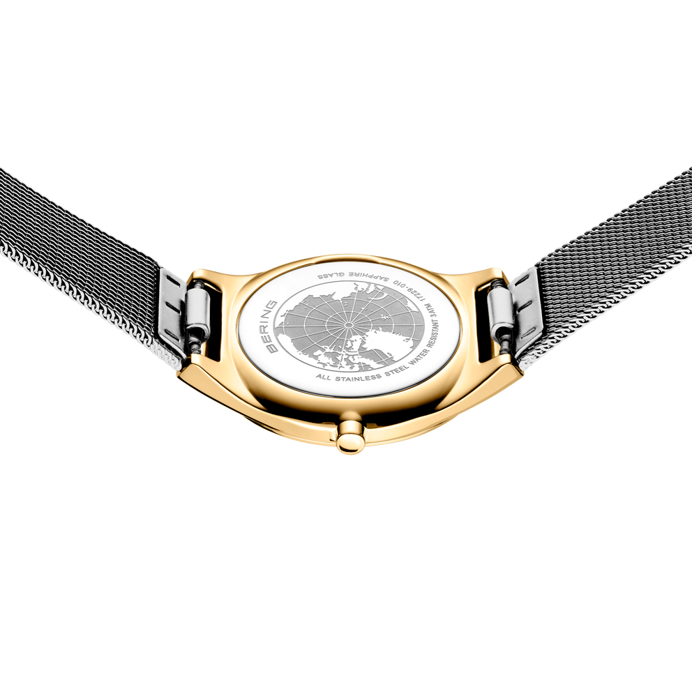 Runde goldfarbene Uhr mit weißem Zifferblatt, Tiermotiv und schwarzem Mesh-Armband, von oben fotografiert