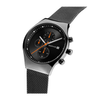 Sort chronografo-ur med orange accenter og mesh-armbånd, set fra siden.