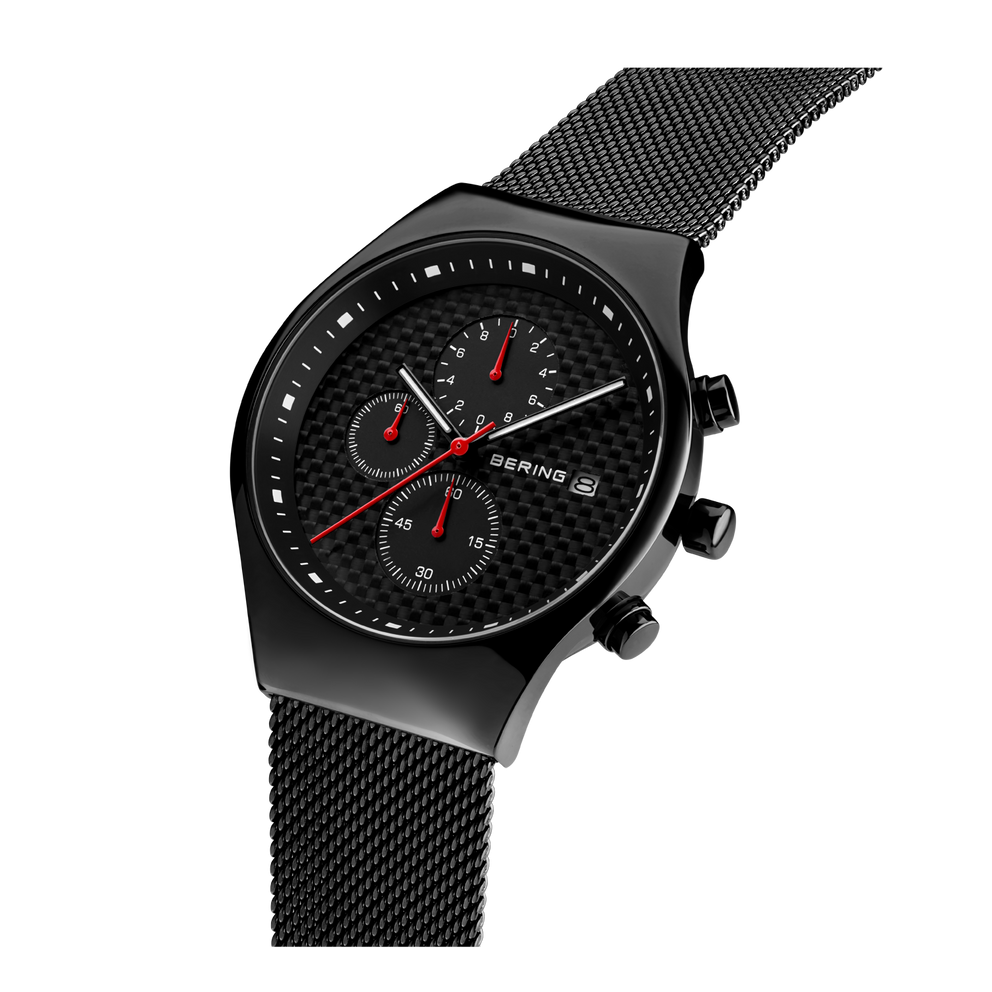 Sort BERING-ur med rundt kabinet, mesh-metallrem og chronograph-skive, skrå sidevisning viser røde accenter